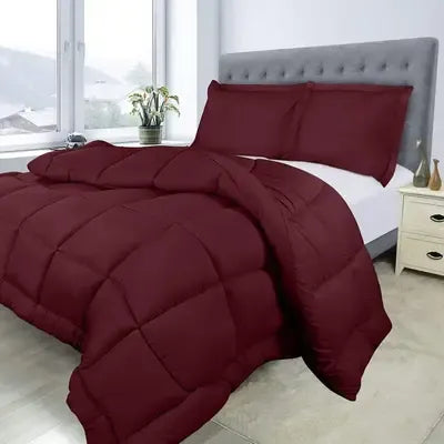Burgundy comforter set on a bed in a bedroom with a window and nightstand.