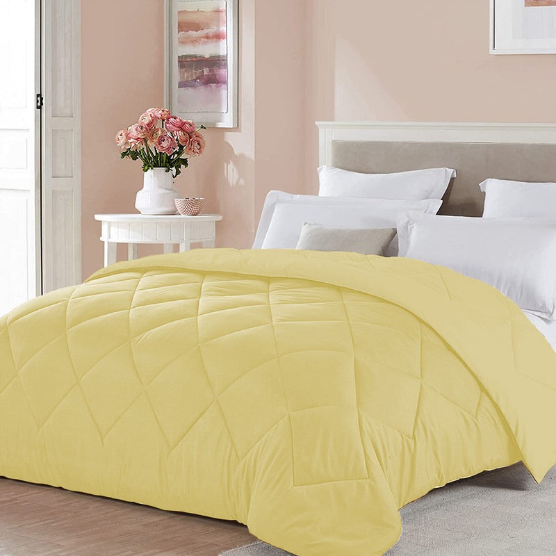Yellow comforter on a bed in a bedroom with pink walls and a vase of flowers.