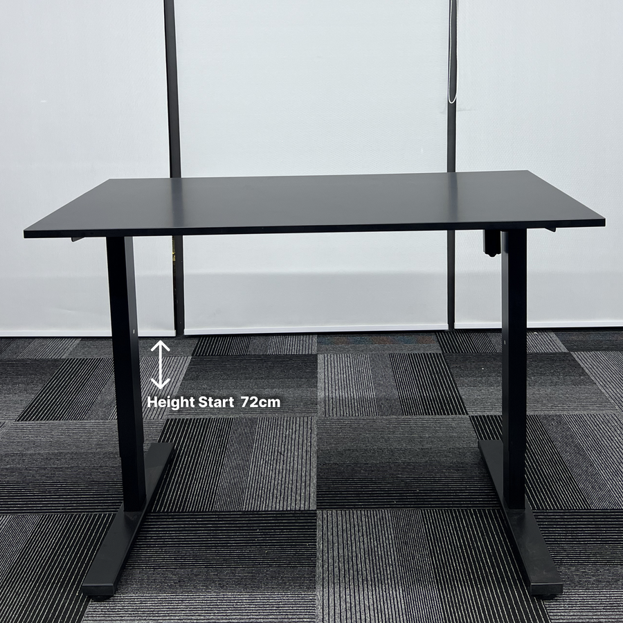 Black adjustable desk on a checkered floor with height measurement text.