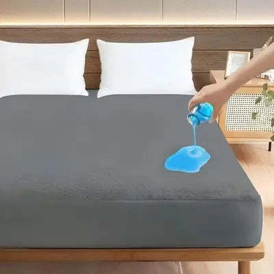 Person applying blue liquid to a gray mattress cover on a bed.
