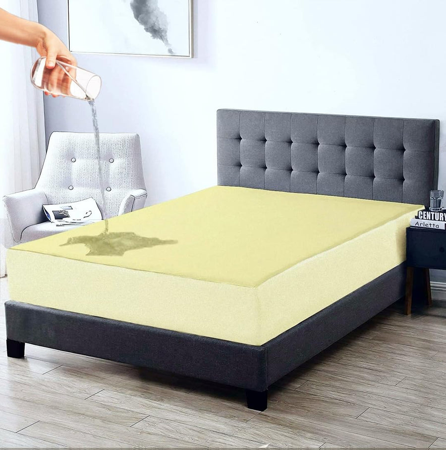Person applying a product to a yellow mattress pad on a bed in a bedroom.
